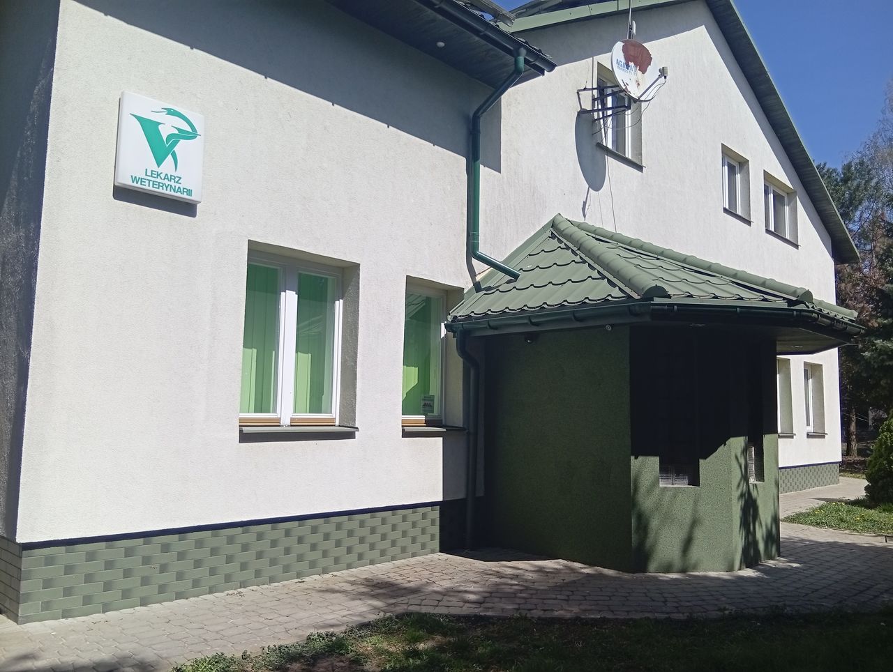 Budynek gabinetu weterynaryjnego w Sitnie, biała elewacja z zielonym dachem i podjazdem